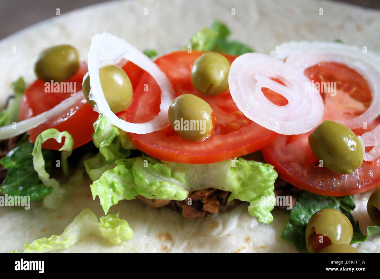 Tortilla with fresh toppings olives, onion, tomato slices, lettuce