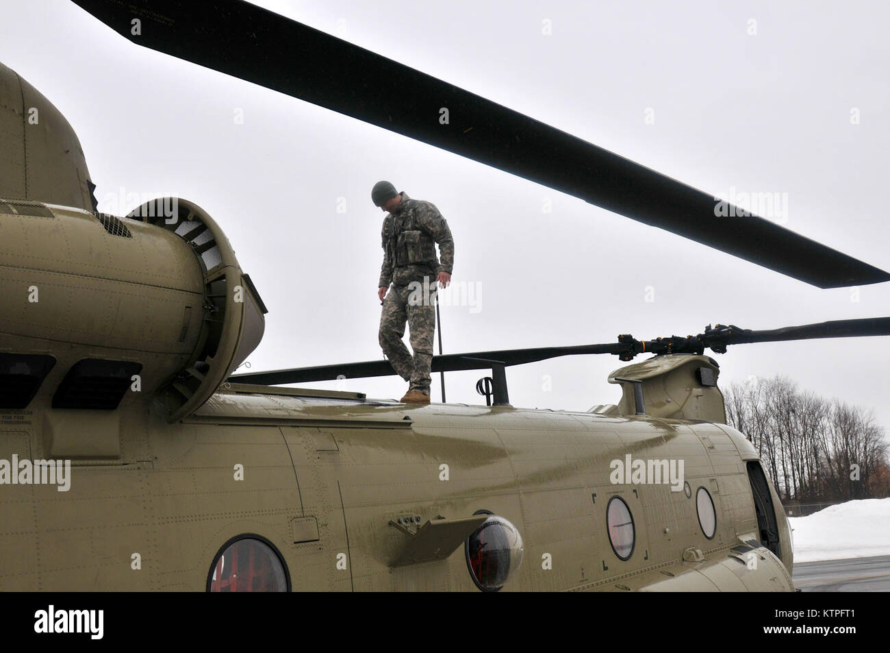 SYRACUSE, NY - Army Staff Sgt. Mike Landaur completes a safety check of a CH-47F Chinook Helicopter on March 14, 2015. Staff Sgt. Landaur is a CH-47F crew chief from Company B, 3rd Battalion, 126th Aviation based at the Army Aviation Support Facility at Rochester International Airport. 30 Airmen from the 274th Air Support Operations Squadron (ASOS), based at Hancock Field Air National Guard Base and the Army aircrew trained together for the first time. The training included Joint Terminal Attack Controller (or JTAC) Airmen from the 274th ASOS conducting CH-47 helicopter familiarization trainin Stock Photo