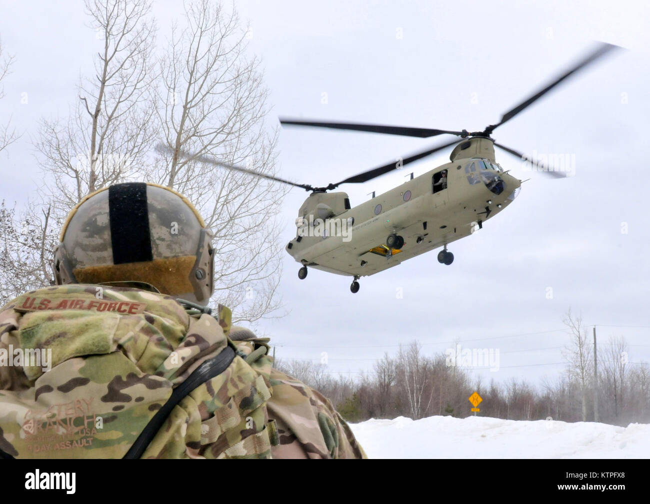 A member of the New York Air National Guard's 274th Air Support Operation Squadron watches as a CH-47F flown by Company B. 3rd Battalion 126th Aviation comes in for a landing at Fort Drum, N.Y. on Saturday, March 14. The two units conducted joint air assault training together.(New York Air National Guard photo by Master Sgt. Eric Miller/Released) Stock Photo