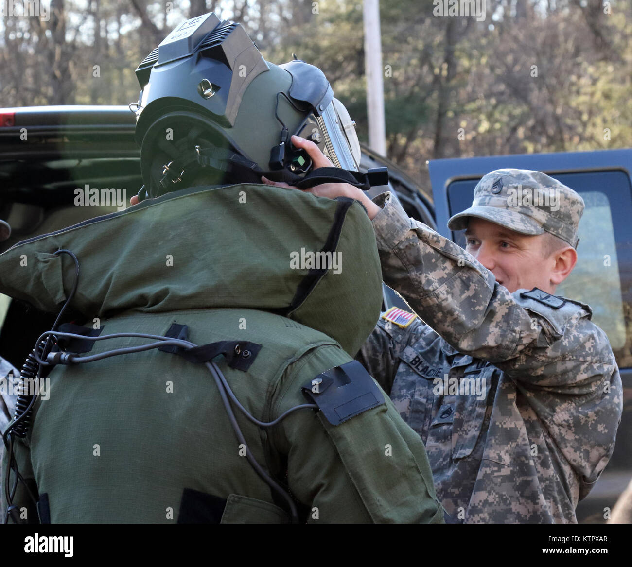 Staff Sgt. Jeremy Blackie, a Soldier in the New York Army National Guard's 1108th Explosive Ordnance Disposal (EOD) Company, puts the bomb disposal suit’s helmet on Staff Sgt. Evan Putman, who is also a Soldier in the 1108th EOD, during a two-day joint training tactical operation with the Columbia-Greene County Shared Services Response Team at the 911 Call Center in Cairo, NY on February 2, 2016. (U.S. Army National Guard photo by Sgt. Michael Davis/Released) Stock Photo