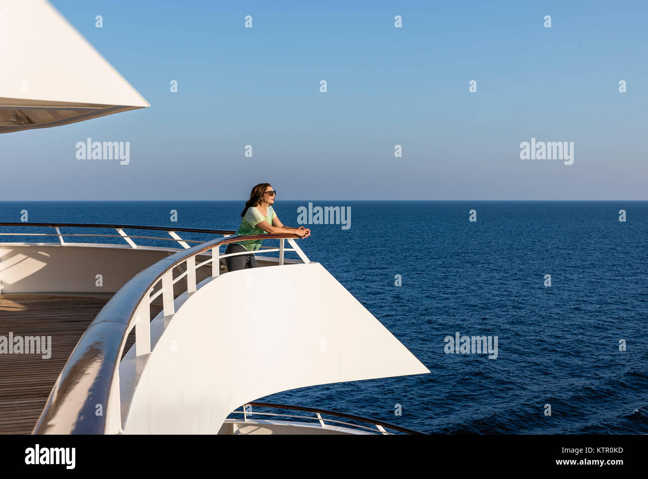 Woman enjoys the ocean view from a yacht deck. Stock Photo