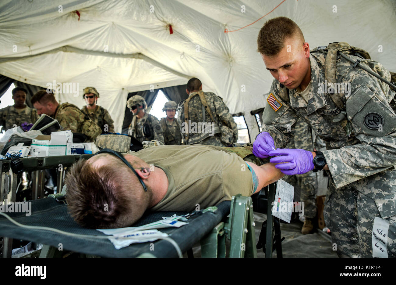 New York Army National Guard Pfc. Beau Fisher, assigned to Headquarters Co., 1st Battalion, 69th Infantry administers IV fluids to a Soldier during a mass casualty exercise at the Army’s Joint Readiness Training Center, Fort Polk, La., Saturday, July 16, 2016. More than 3,000 New York Army National Guard Soldiers deployed for a three week exercise at the Army’s Joint Readiness Training Center, July 9-30, 2016. U.S. Army National Guard photo by Sgt. Harley Jelis. Stock Photo