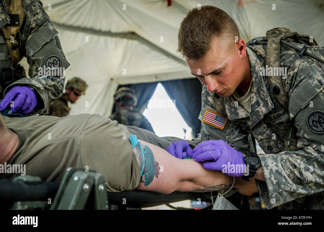 New York Army National Guard Pfc. Beau Fisher, assigned to Headquarters Co., 1st Battalion, 69th Infantry, administers IV fluids to a Soldier during a mass casualty exercise at the Army’s Joint Readiness Training Center, Fort Polk, La., Saturday, July 16, 2016. More than 3,000 New York Army National Guard Soldiers deployed for a three week exercise at the Army’s Joint Readiness Training Center, July 9-30, 2016. U.S. Army National Guard photo by Sgt. Harley Jelis. Stock Photo