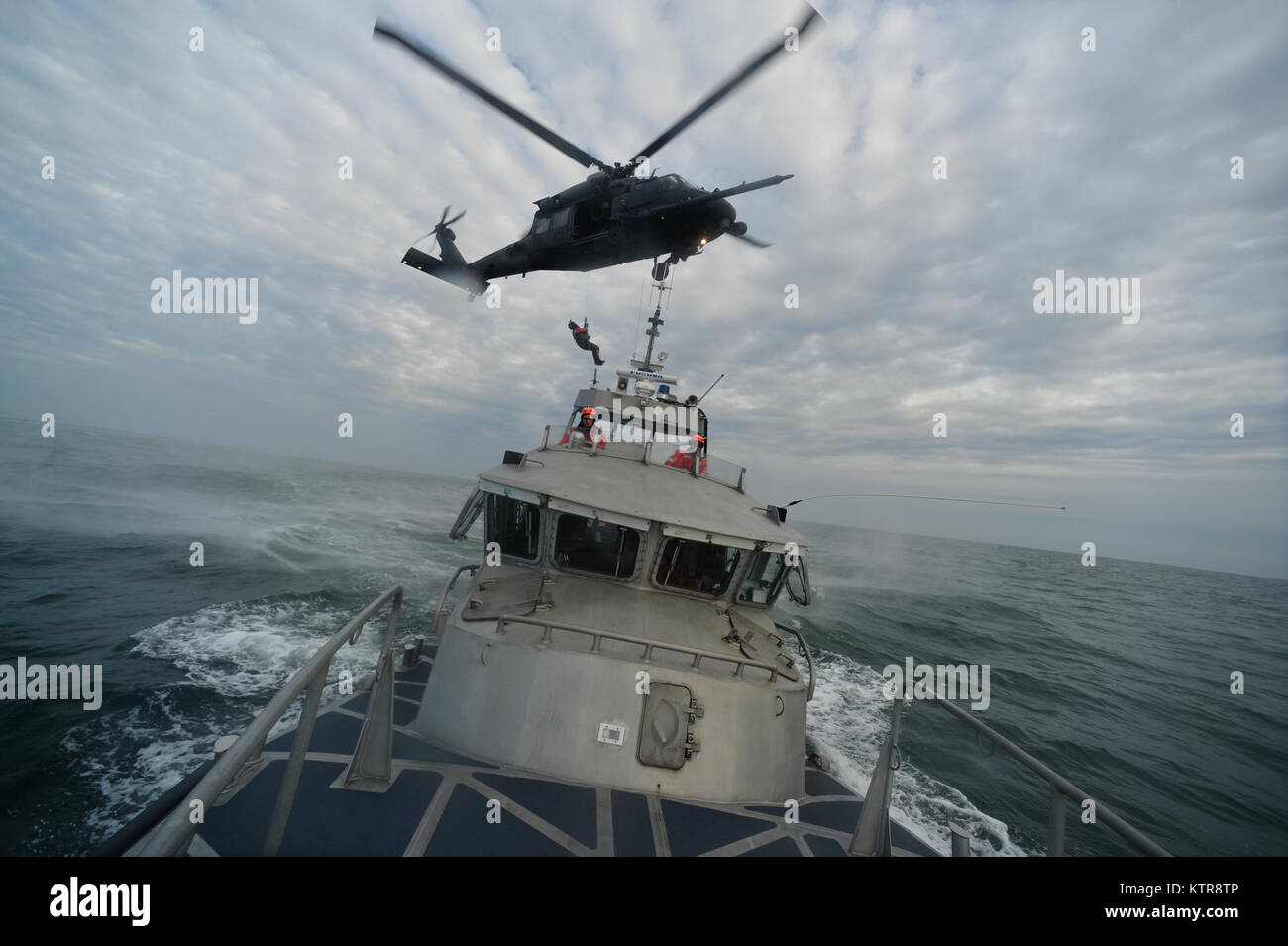 HAMPTON BAYS, NY - Airmen with 101st Rescue Squadron and 103rd Rescue Squadron conduct hoist training with United States Coastguardsmen from  US Coast Guard Station Shinnecock December 22, 2016.  During this training, Guardian Angels from the 103rd RQS were lowered via hoist from an HH-60 Pavehawk onto the cutter's deck. After that, the aircraft practiced dropping and removing patient litters, before hoisting the Guardian Angels back up and returning to base.  (US Air National Guard / Staff Sergeant Christopher S. Muncy / released) Stock Photo