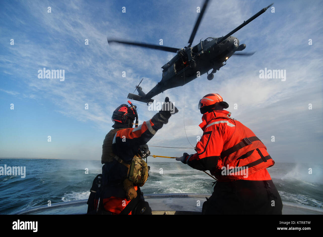 HAMPTON BAYS, NY -  Machinery Technician 2nd Class Benjamin Esposita helps wrangle a hoist line from an HH-60 Pavehawk from the 101st Rescue Squadron during training in the waters near US Coast Guard Station Shinnecock December 22, 2016.  During this training, Guardian Angels from the 103rd RQS were lowered via hoist from an HH-60 Pavehawk onto the cutter's deck. After that, the aircraft practiced dropping and removing patient litters, before hoisting the Guardian Angels back up and returning to base.  (US Air National Guard / Staff Sergeant Christopher S. Muncy / released) Stock Photo