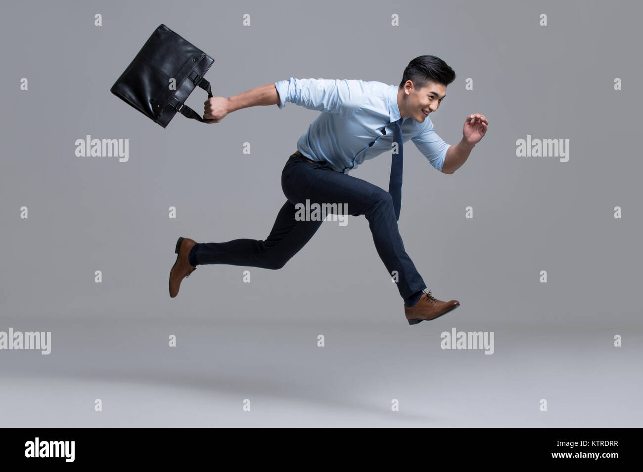 Cheerful young businessman running with briefcase Stock Photo - Alamy