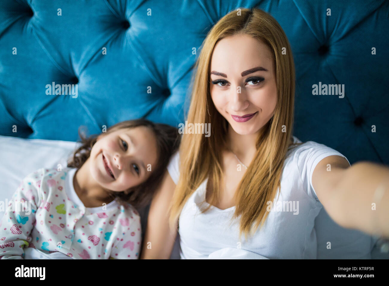 Happy mother and daughter taking selfie with smartphone on bed Stock Photo Alamy