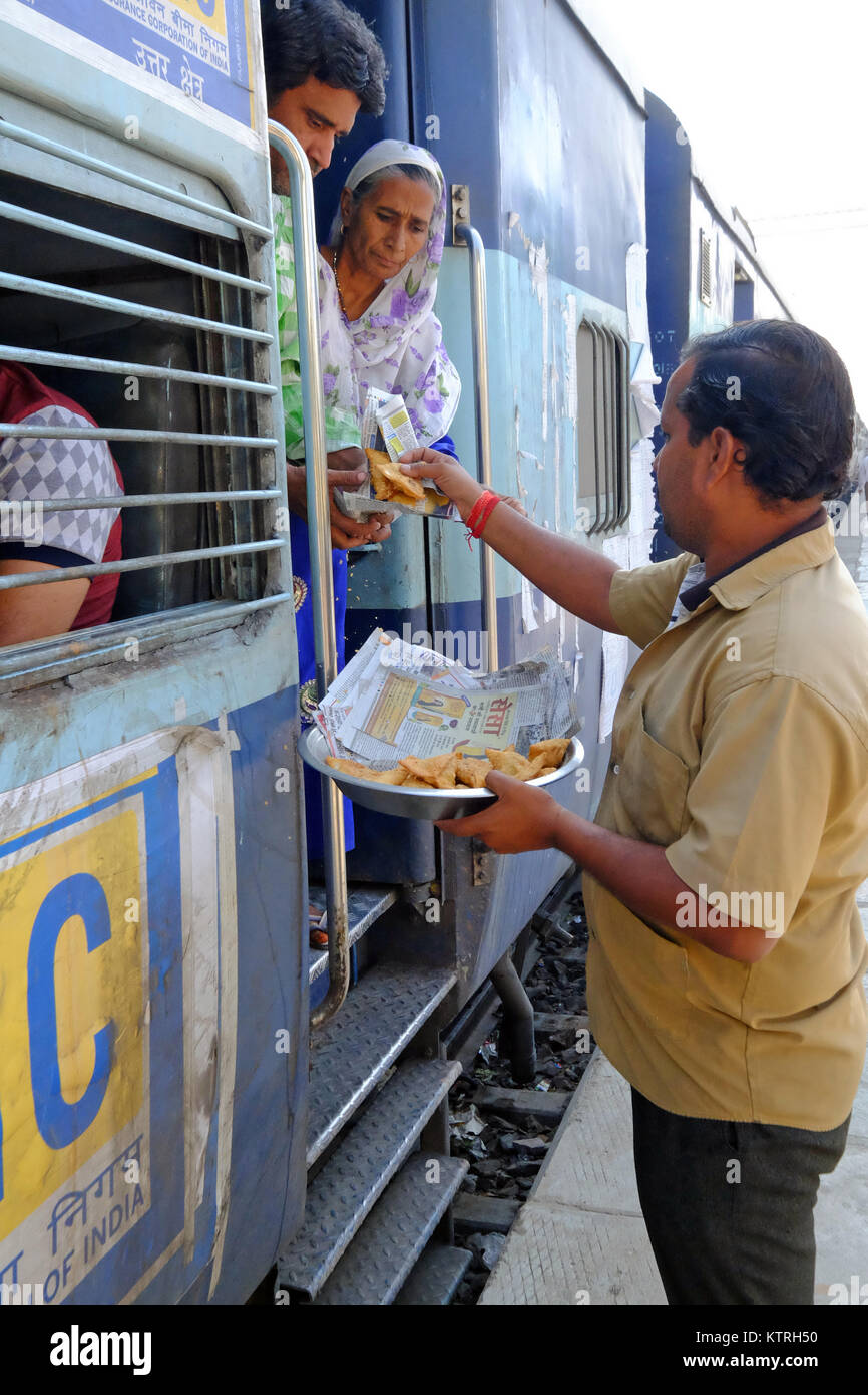 Hawker selling snacks to rail passengers at Indian railway station Stock Photo