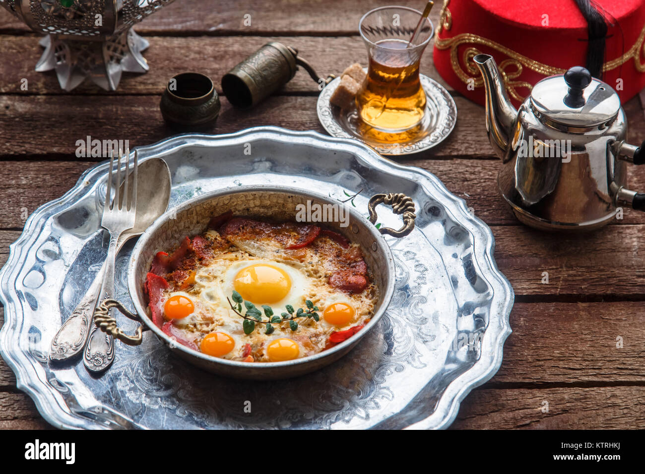 Traditional turkish breakfast with eggs and pastirma, with tea and metal dishware Stock Photo