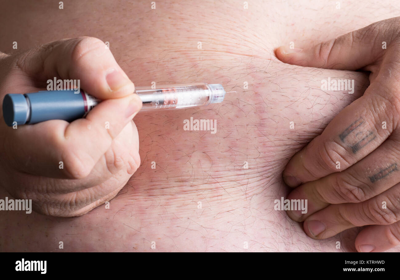 insulin being administered via an insulin pen into large mans stomach. Stock Photo