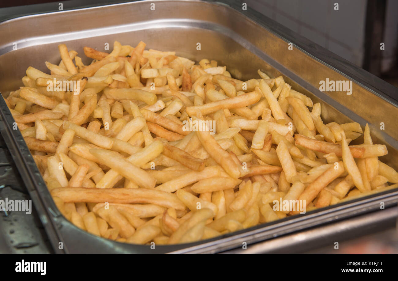 Large tray of cooked fast food French fries chips in silver metal