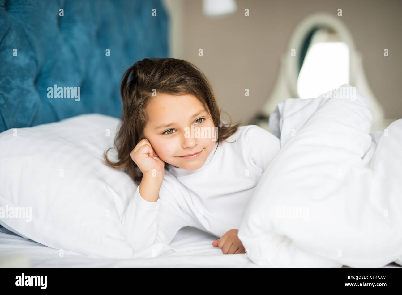 Closeup portrait of beautiful little kid lying on bed with hand under