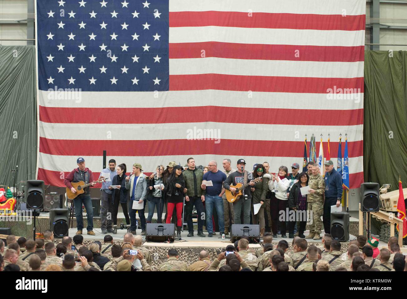 U.S. Army Medal of Honor Recipient Florent Groberg, actor Adam Devine, comedian Iliza Shlesinger, World Wrestling Entertainment (WWE) wrestlers Alicia Fox, Gail Kim and The Miz (Michael Mizanin), professional chef Robert Irvine, U.S. Joint Chiefs of Staff Chairman Joseph Dunford and country music singer Jerrod Niemann perform on stage for U.S. soldiers during the USO Holiday Tour at the Bagram Airfield December 24, 2017 in Bagram, Afghanistan. Stock Photo