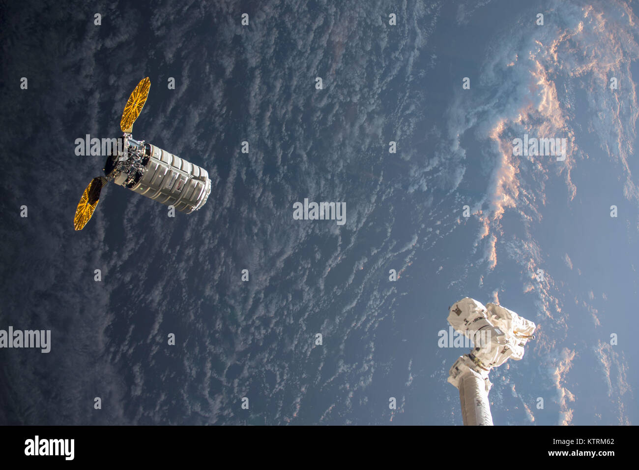 Orbital ATK's Cygnus resupply ship with its cymbal-ike UltraFlex solar arrays approaches the International Space Station's robotic arm Canadarm2 as both spacecraft fly into an orbital sunrise on Nov. 14, 2017 Stock Photo