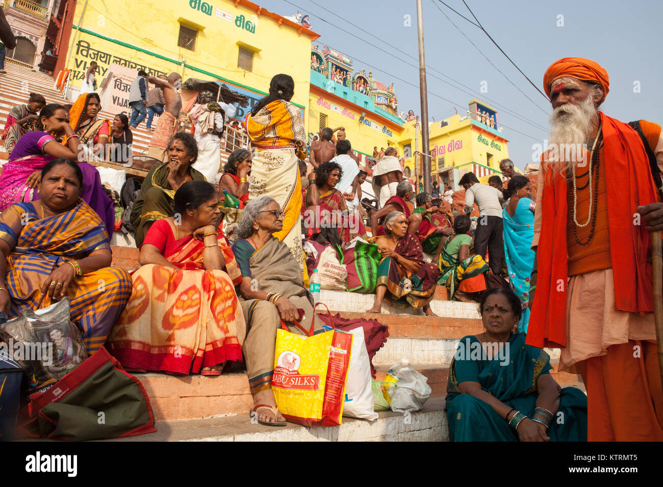Pilgrims and a saddhu on Kesar Ghat beside the River Ganges in Varanasi Stock Photo