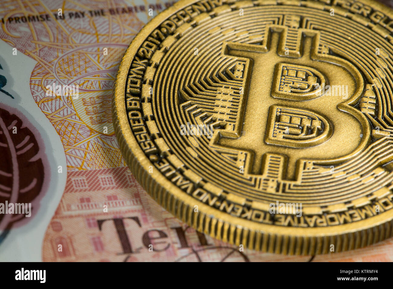 Gold Bitcoin coin on a tenner ten pound note Stock Photo