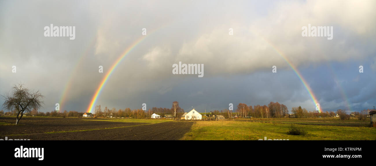 rainbow over the village houses and fields Stock Photo
