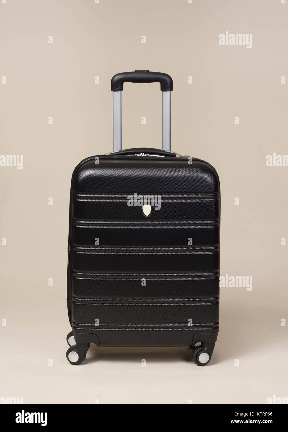 Small Black trolley suitcase bag isolated on beige background Stock Photo