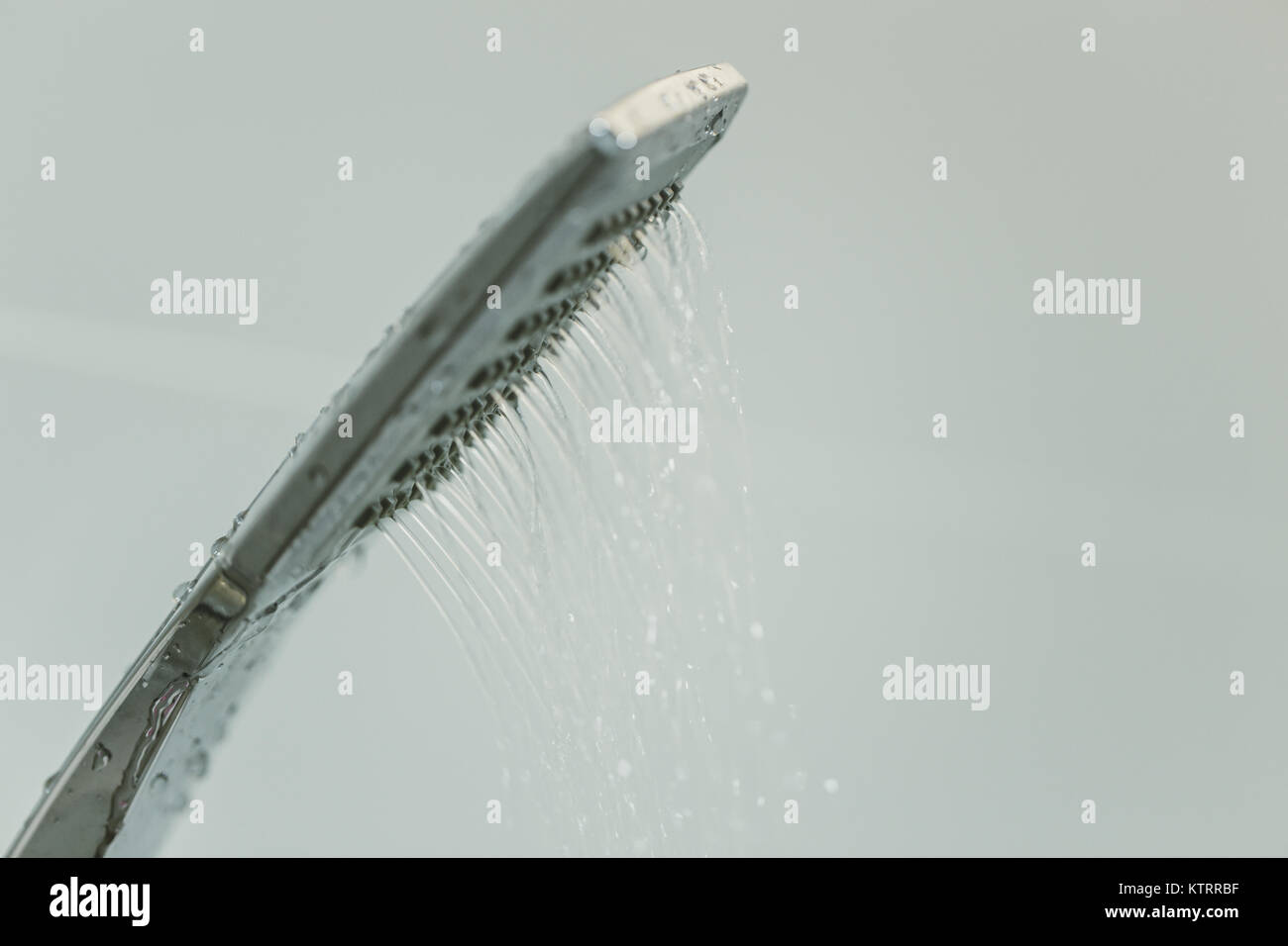 Low water pressure problem closeup at shower head in white bathroom