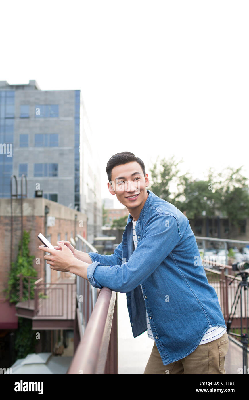 Cheerful young man holding a smart phone Stock Photo - Alamy
