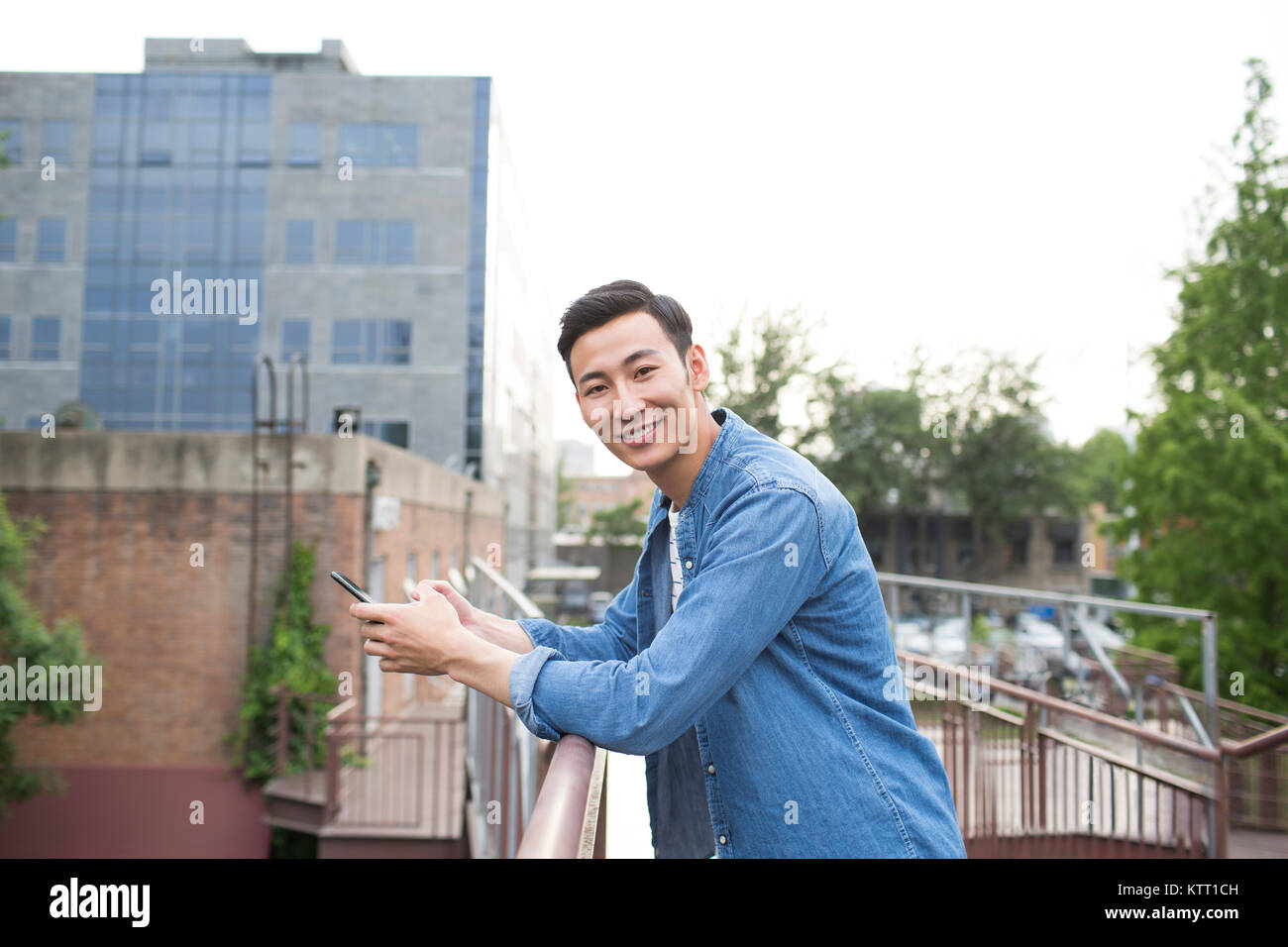 Cheerful young man holding a smart phone Stock Photo - Alamy