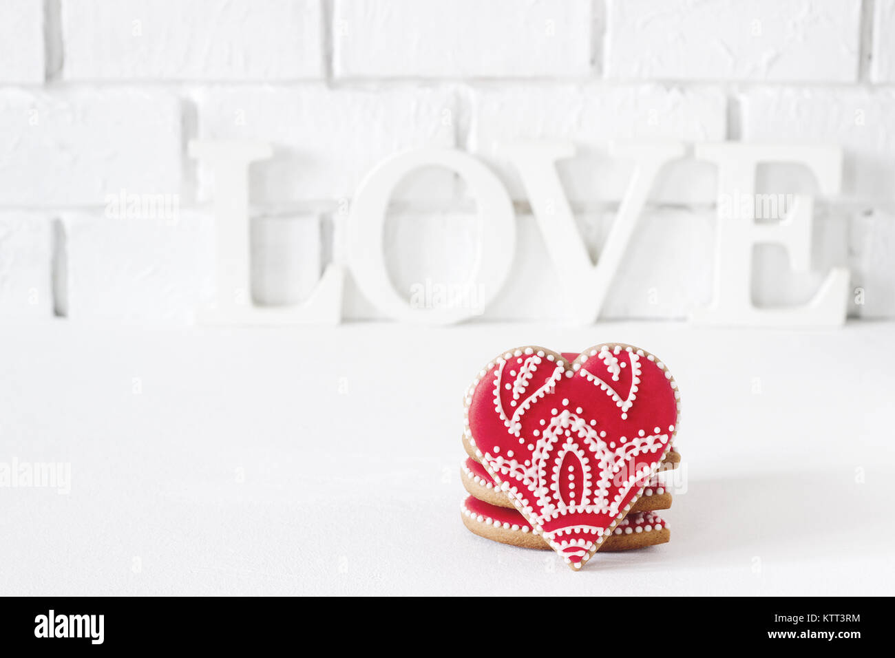 Red gingerbread heart on a white background with an inscription love. Postcard to the day of St. Valentine. Selective focus. Stock Photo