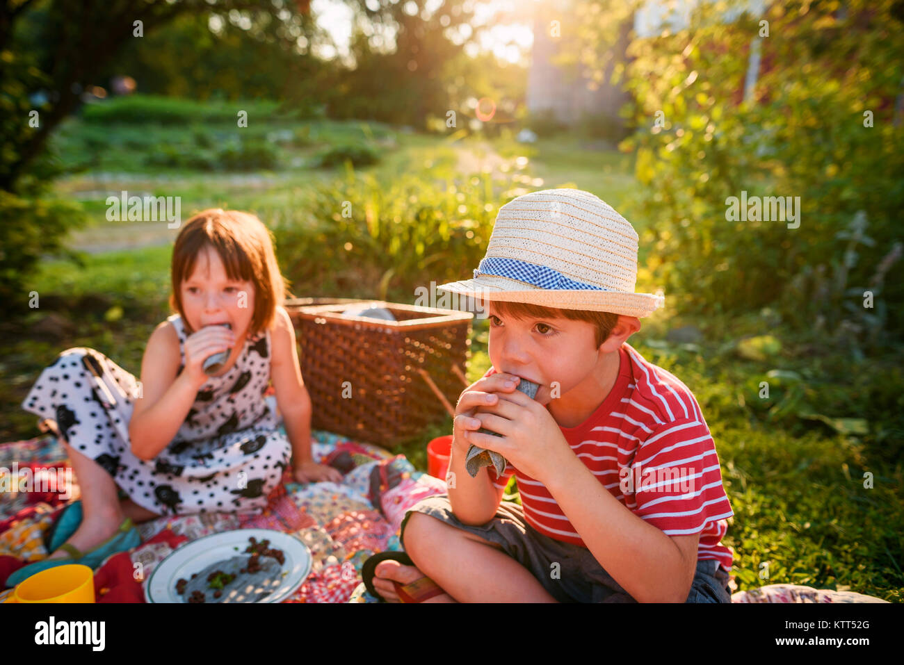 Boy and girl sitting in garden having a picnic Stock Photo