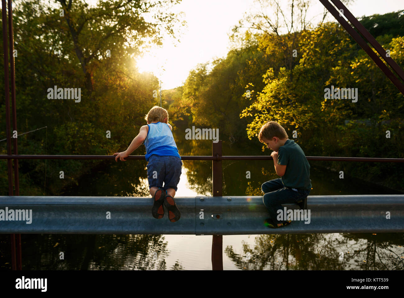 Two boys standing on a bridge fishing Stock Photo - Alamy