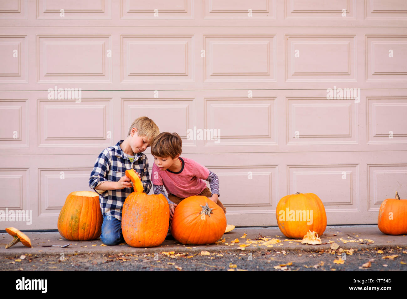 Two boys sitting outdoors carving Halloween pumpkins Stock Photo