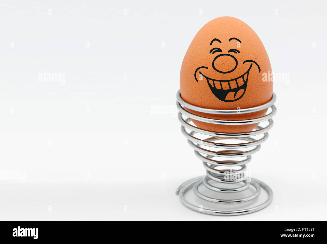 An egg in an egg cup with a smiley face laughing Stock Photo