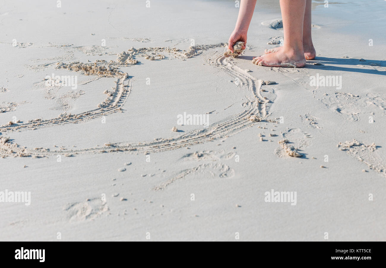 Girl drawing in the sand on the beach, Australia Stock Photo