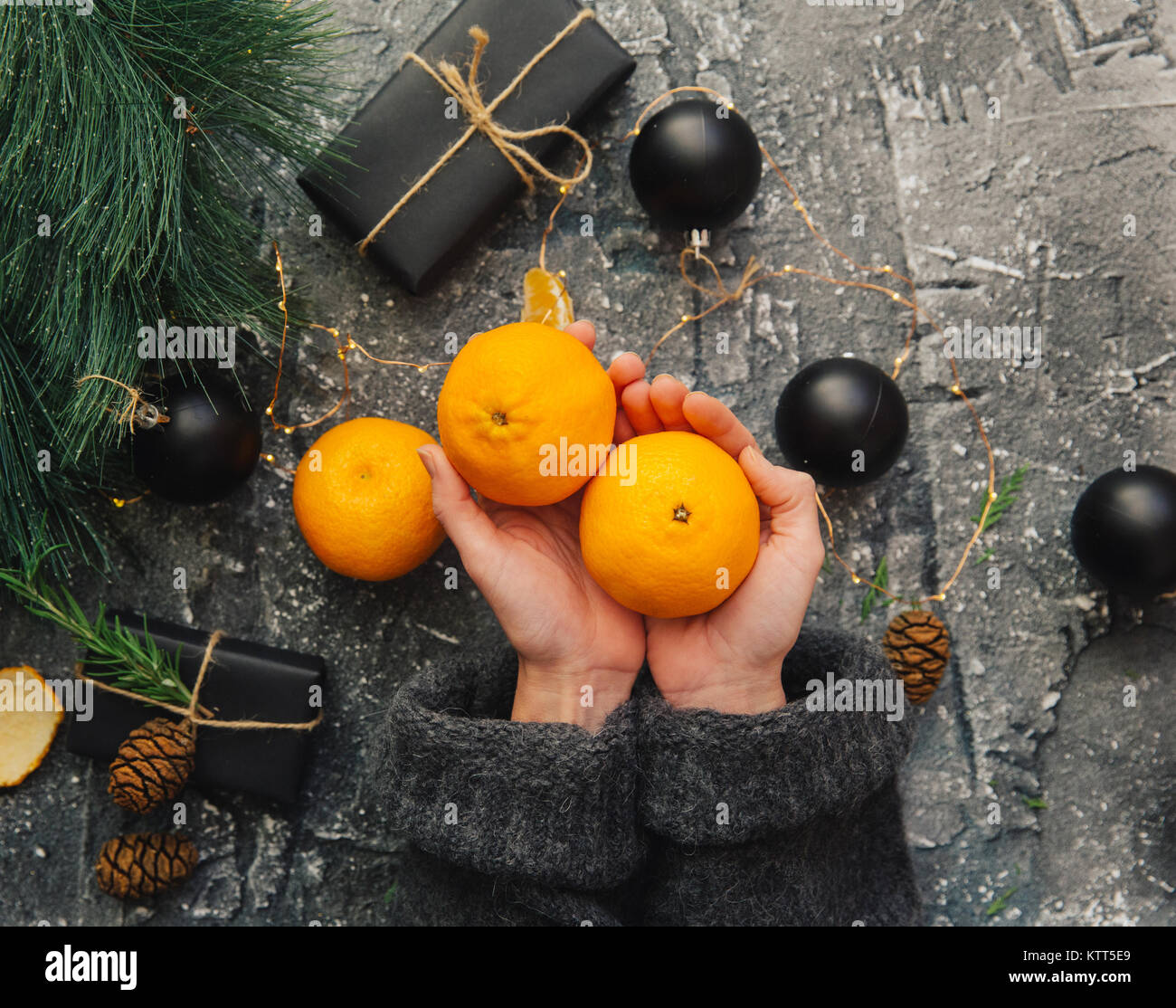 Woman's hands holding fresh satsumas and Christmas gifts Stock Photo