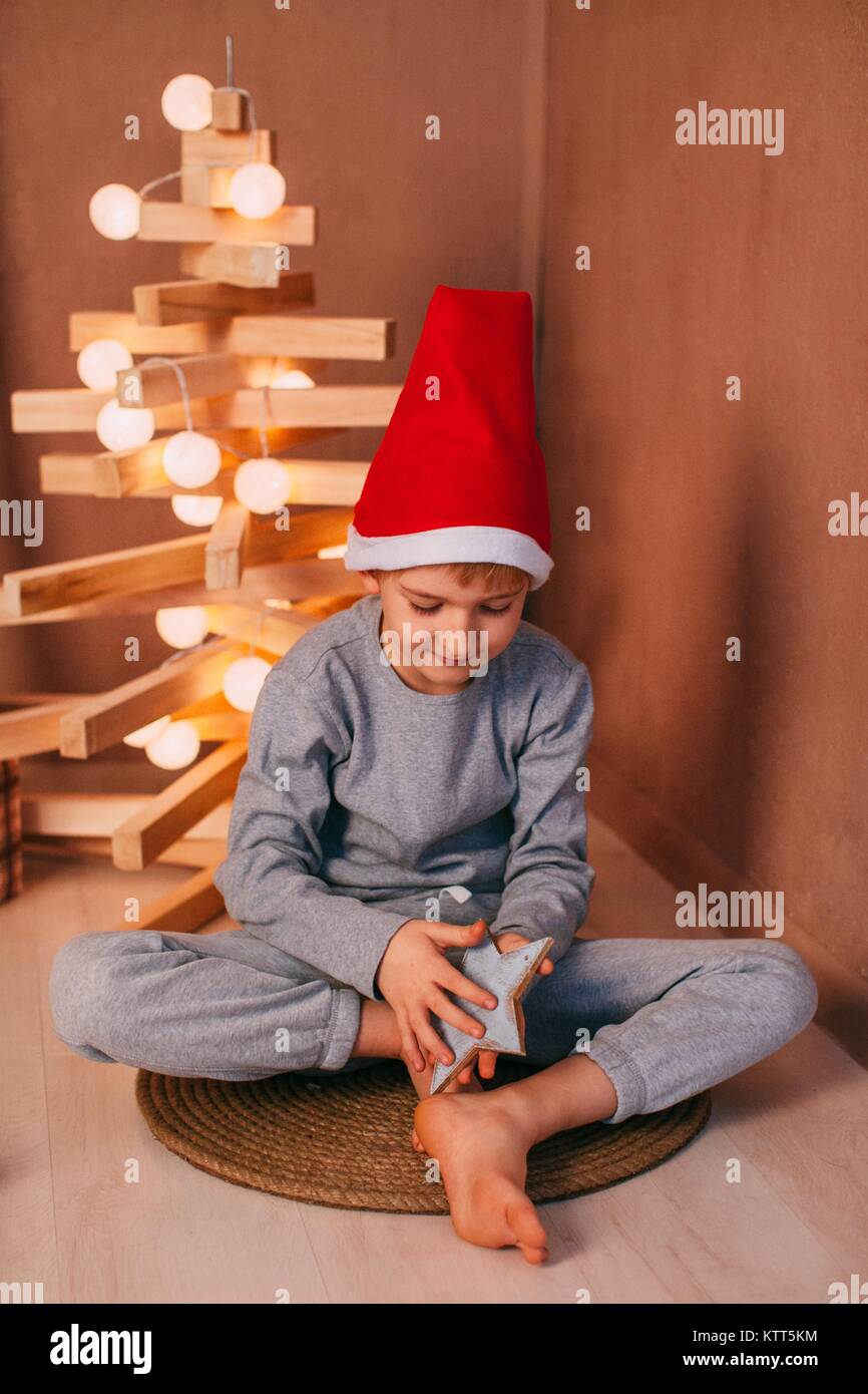 Boy sitting on floor next to a modern Christmas tree installation Stock Photo