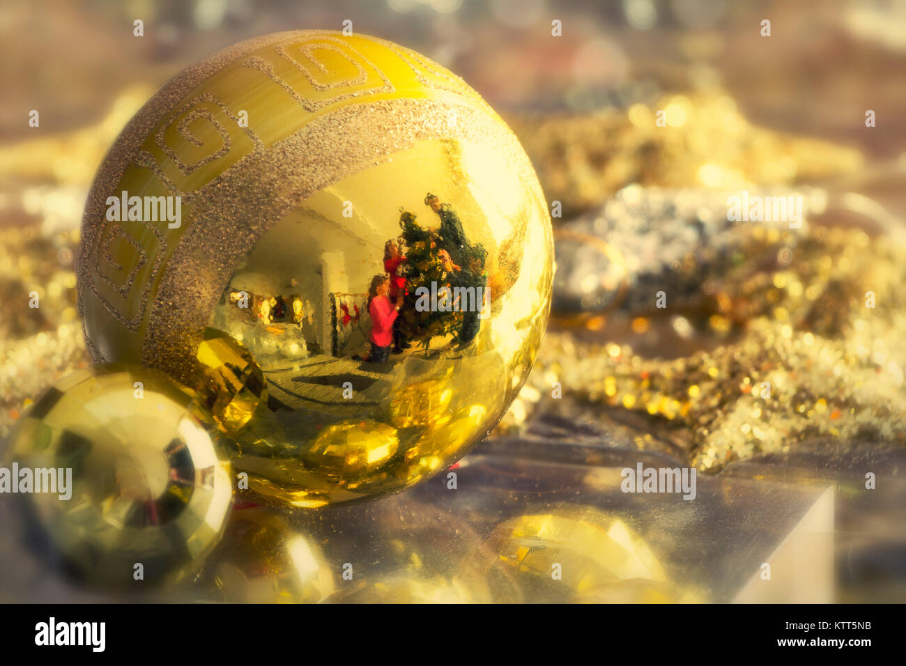 Reflection of a family decorating a Christmas tree in a bauble Stock Photo