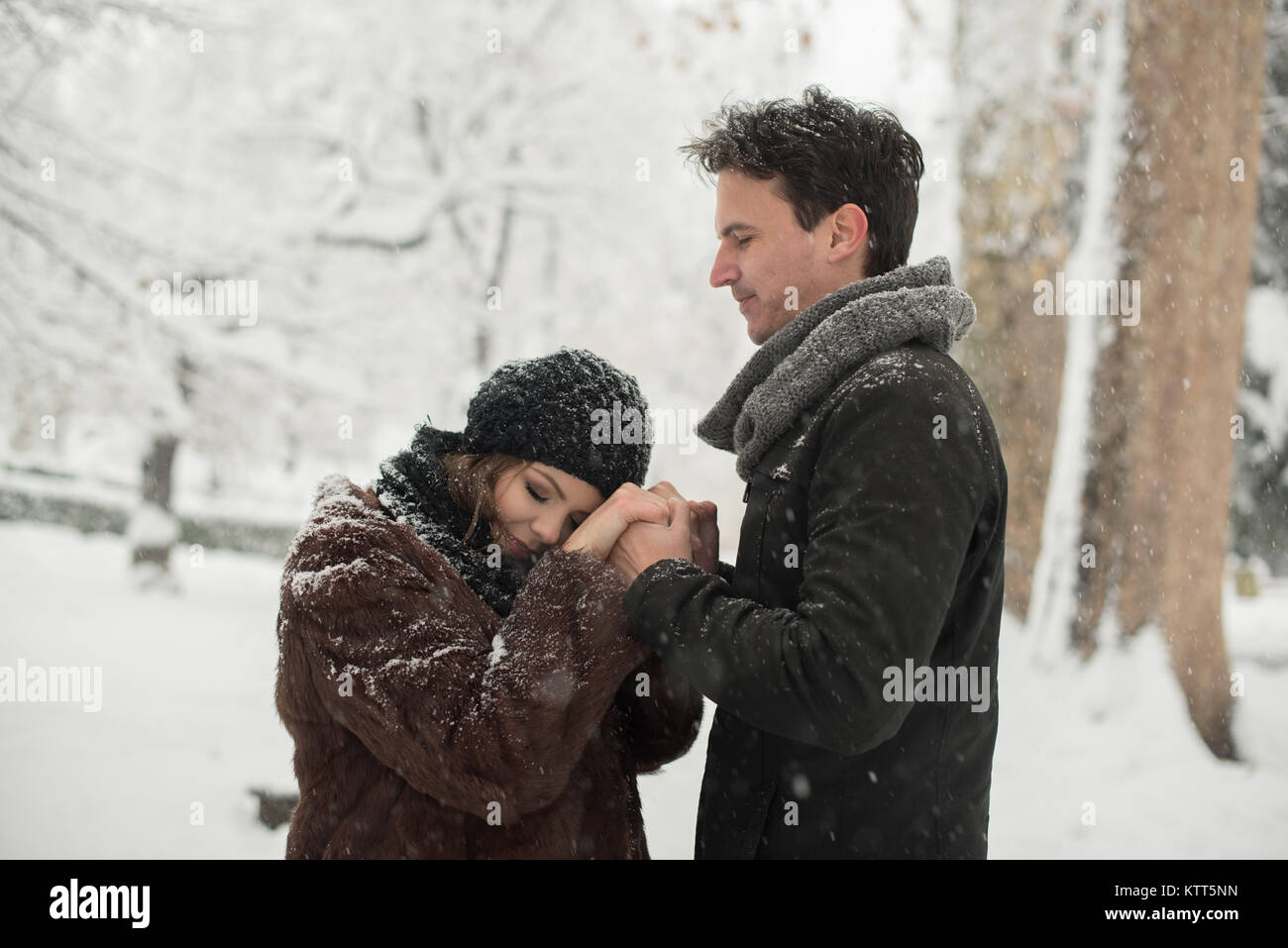 Couple standing in park holding hands in the snow Stock Photo