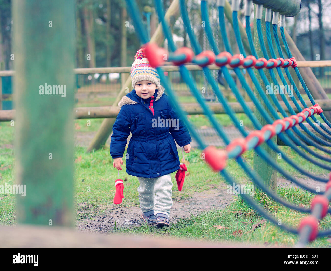 Girl walking next to a climbing frame in a playground Stock Photo