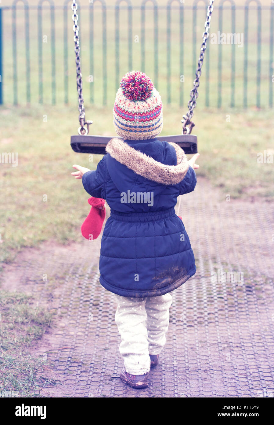 Girl pushing a swing in a playground Stock Photo