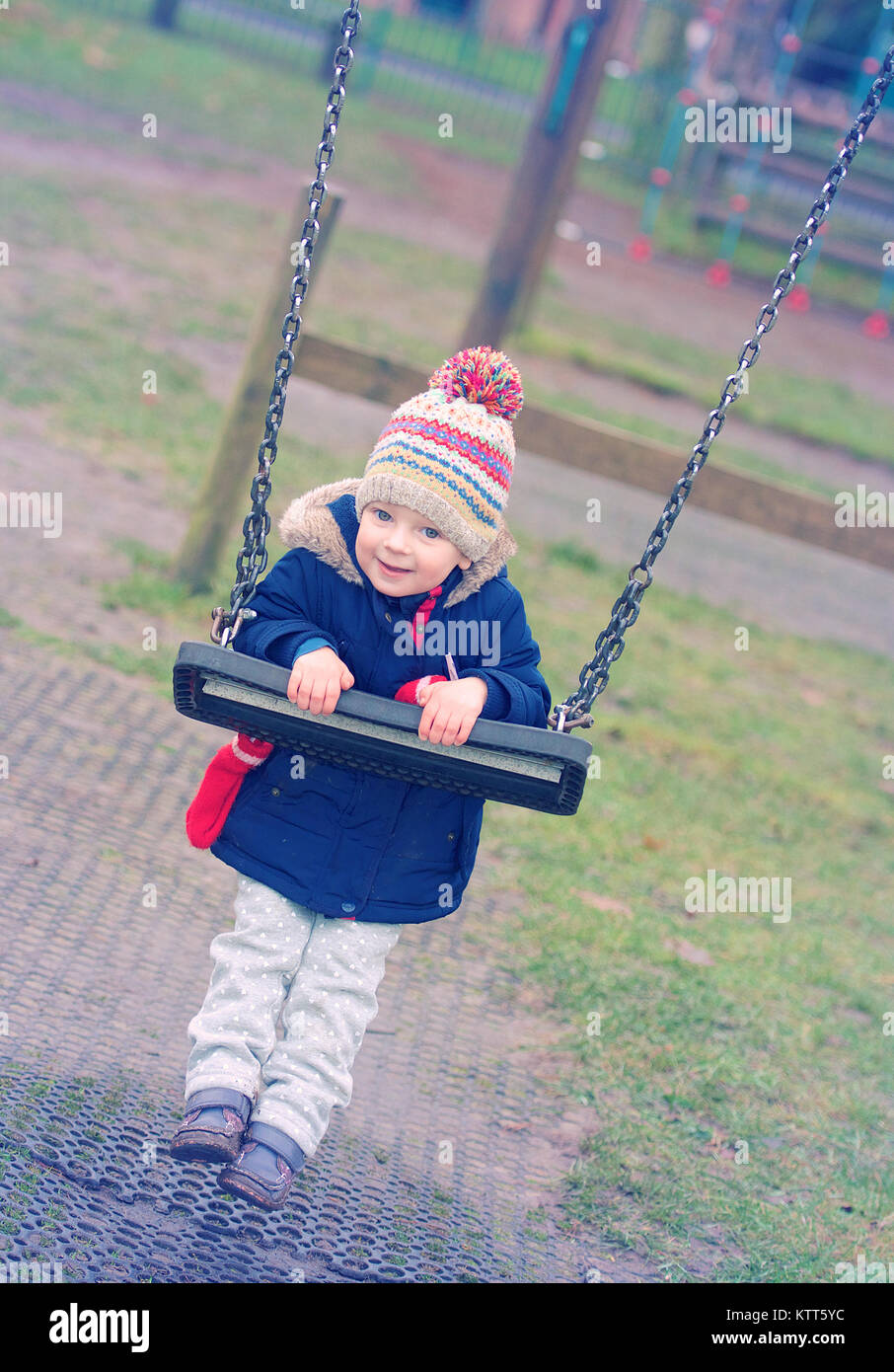 Girl hanging on a swing in the playground Stock Photo