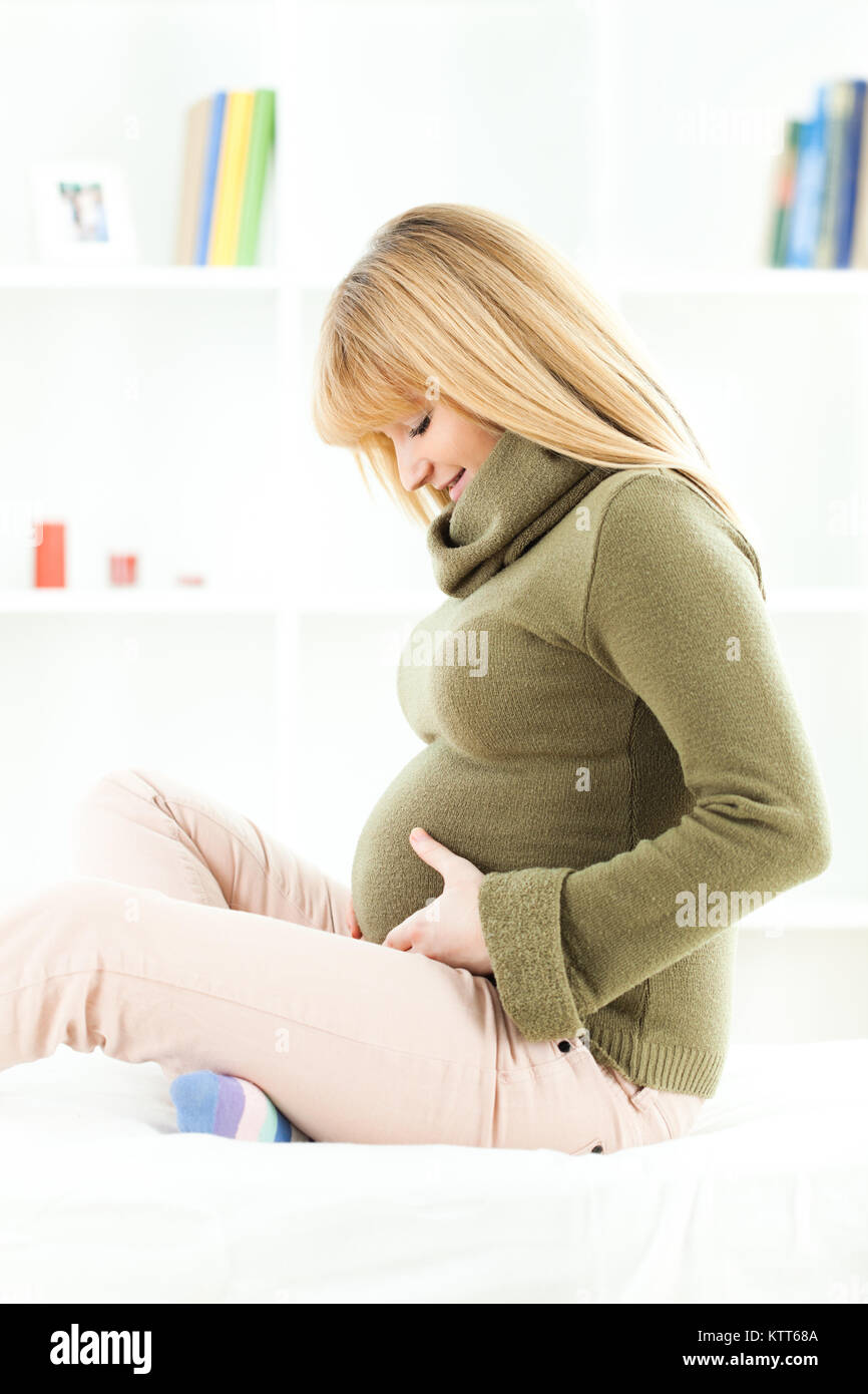 Happy pregnant woman holding her stomach and smiling Stock Photo - Alamy