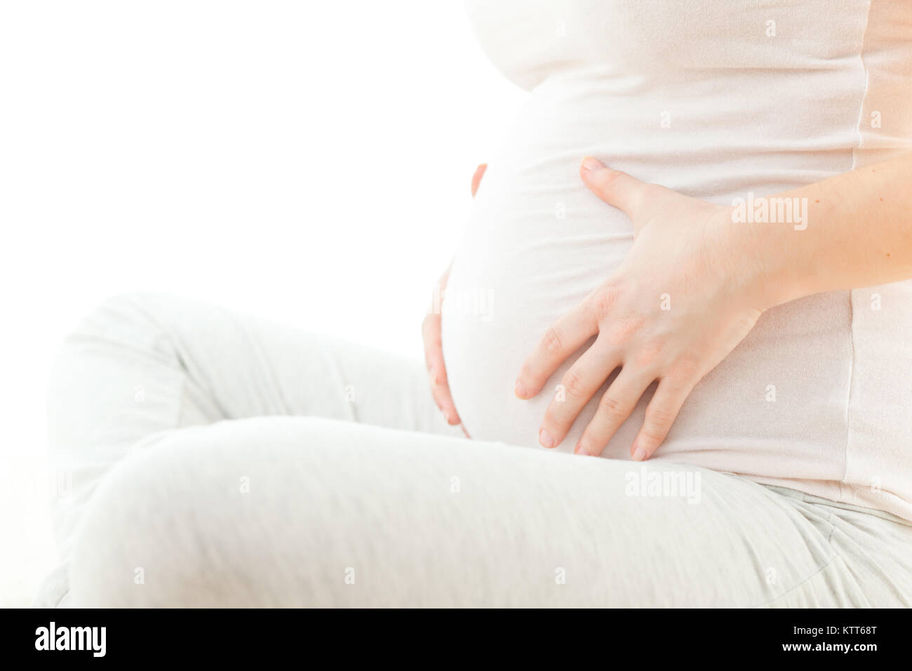 Pregnant woman holding her stomach Stock Photo - Alamy