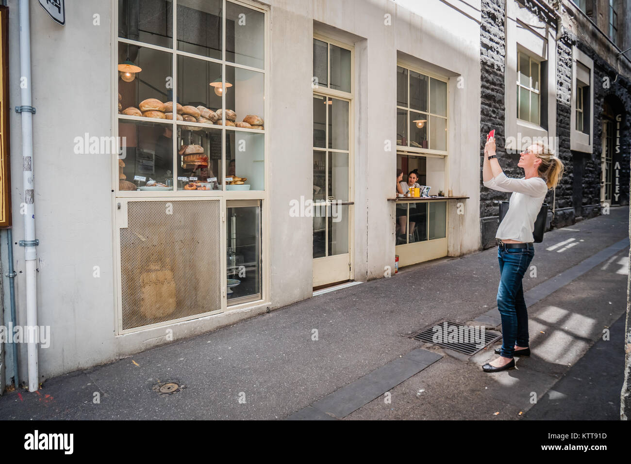 female tourist taking picture melbourne bakery shop Stock Photo