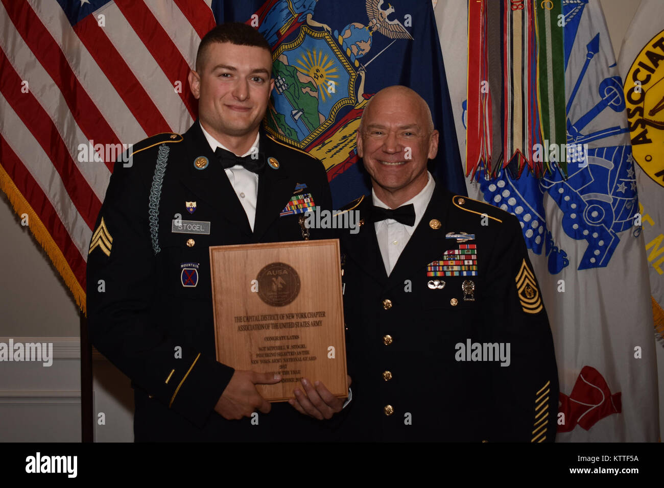 N.Y. Army National Guard Soldier Sgt. Mitchell Stogel, assigned to Scout platoon, 1st battalion, 69th infantry, receives the Non-Commisioned Officer of the Year award next to the N.Y. State Command Sgt. Maj. David Piwowarski, at the Association of the United States Army’s(AUSA) Soldier Recognition dinner, in Albany, N.Y., Sept. 23, 2017. Stogel received this award for his achievements as an NCO in the N.Y. Army National Guard. (N.Y. Army National Guard photo by Pfc. Andrew Valenza) Stock Photo