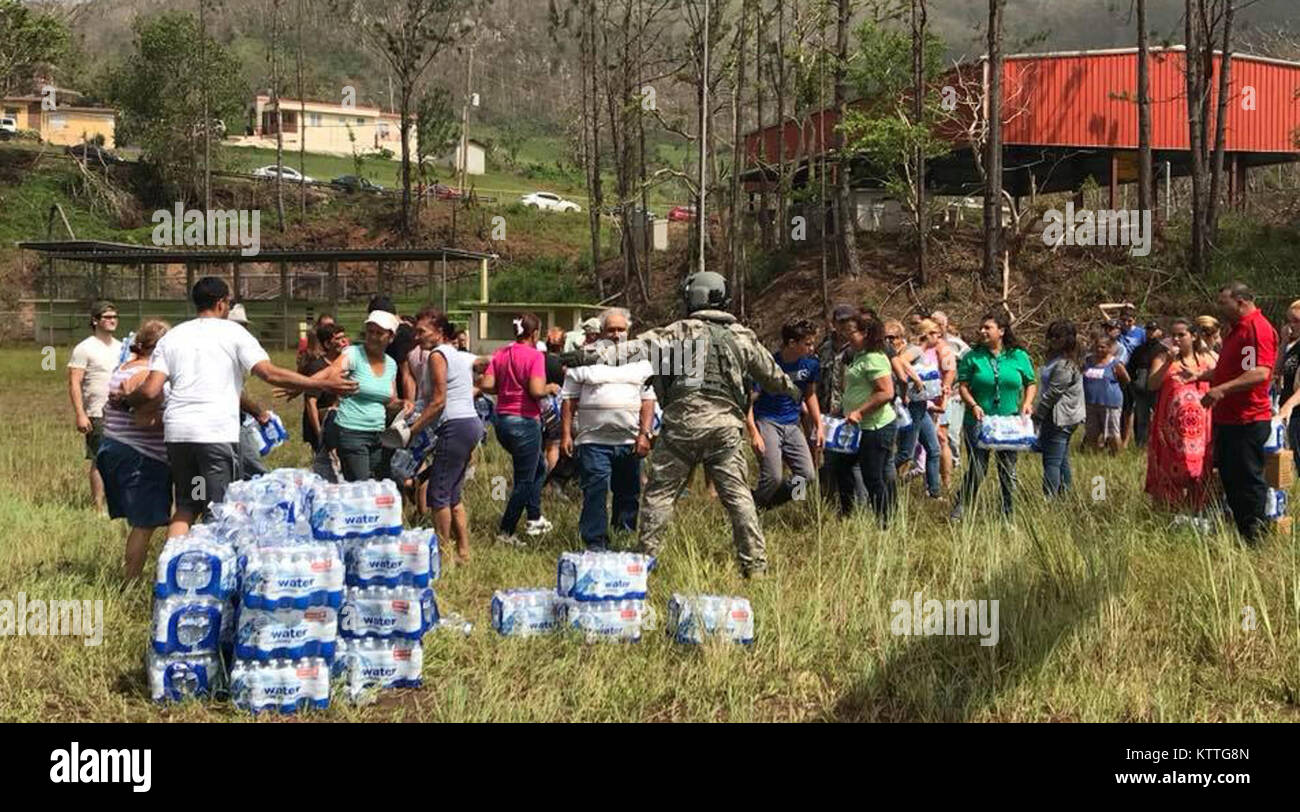 Soldiers of the 3rd Battalion, 142nd Aviation, distribute water to local residents during an aid mission in Puerto Rico on Oct. 19. 2017.The 3rd Battalion, 142nd Aviation deployed 60 personnel and four UH-60 helicopters to Puerto Rico to provide relief and assistance following Hurricane Maria. Stock Photo