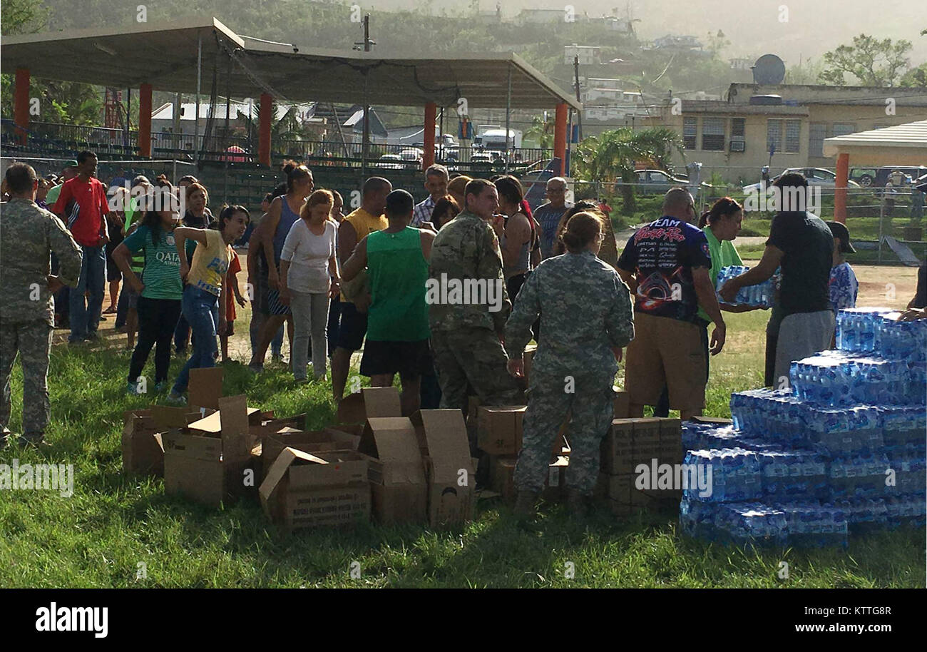 Soldiers of the 3rd Battalion, 142nd Aviation, distribute water to local residents during an aid mission in Puerto Rico on Oct. 19. 2017.The 3rd Battalion, 142nd Aviation deployed 60 personnel and four UH-60 helicopters to Puerto Rico to provide relief and assistance following Hurricane Maria. Stock Photo