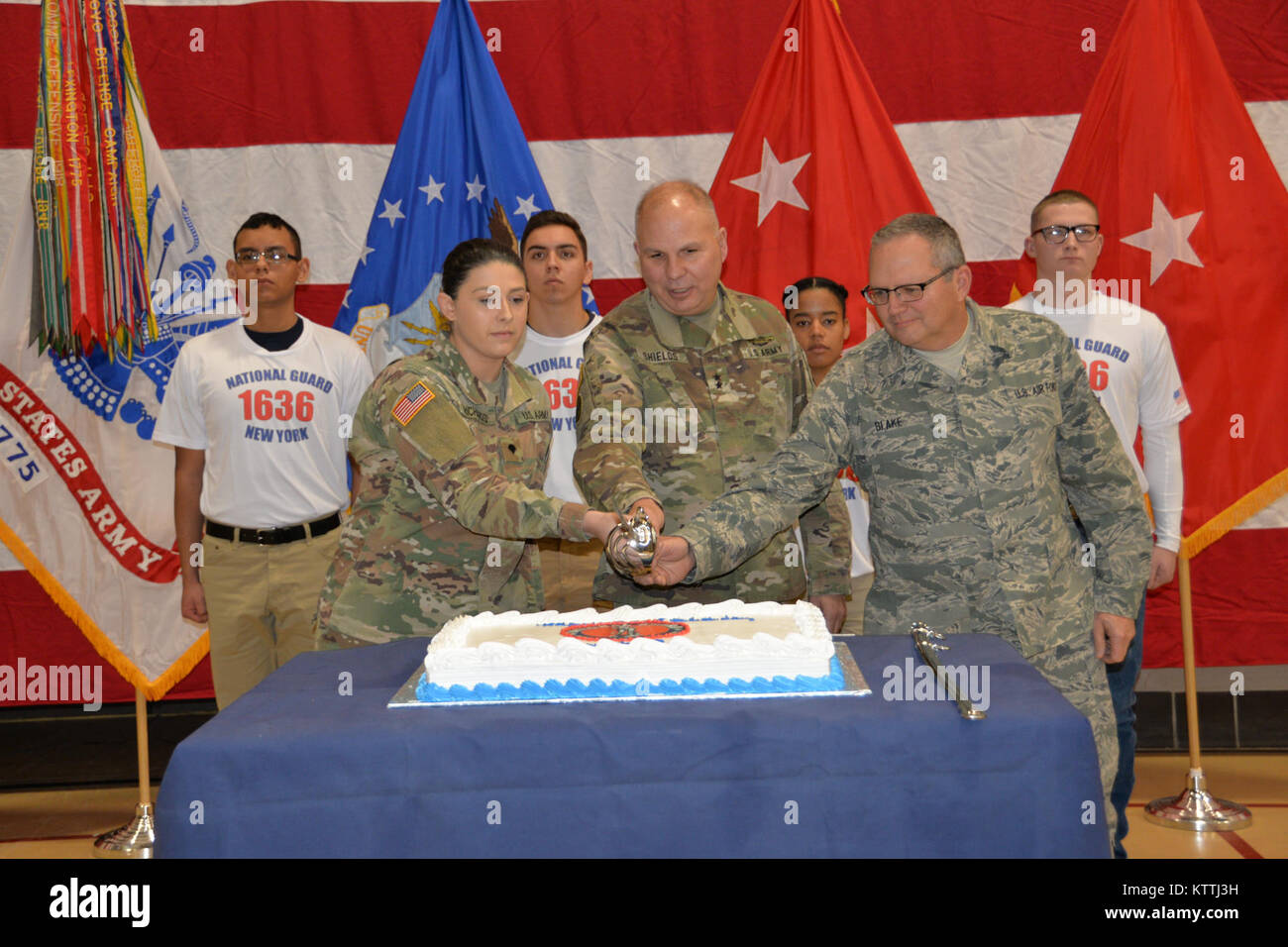 Maj. Gen. Raymond Shields, assistant adjutant general, Army, of New York (middle) joins the oldest and newest members of the New York National Guard to cut a cake in celebration of the National Guard’s 381th birthday at New York National Guard headquarters in Latham, N.Y. on December, 13 2017. The National Guard was established in 1636 and is the oldest military force in the Department of Defense. The new and old members are Spc. Jade Richards, age 19, New York Army National Guard (left); Chief Master Sgt. Michael Blake, one of the New York Air National Guard’s oldest serving Soldiers (right). Stock Photo