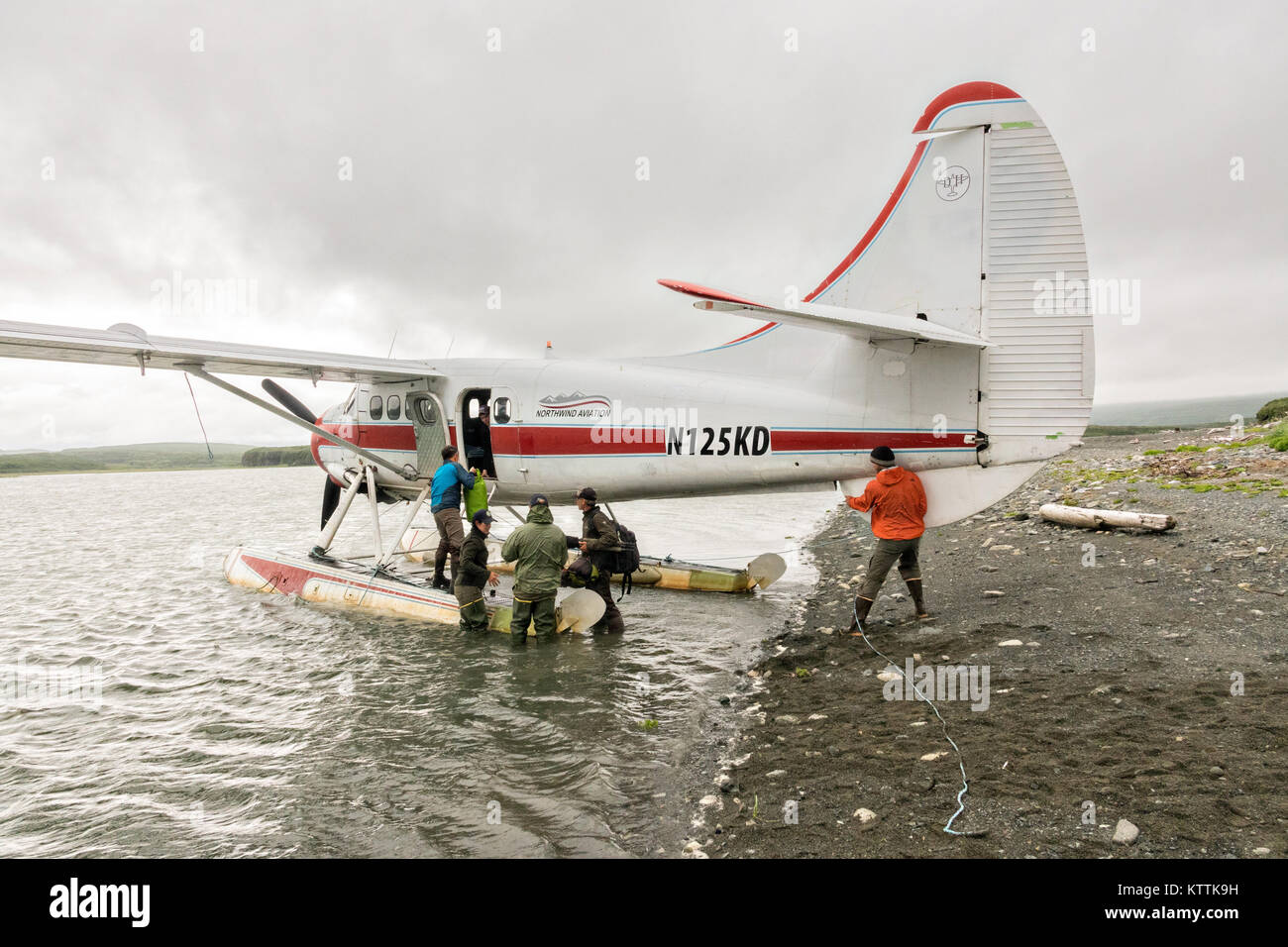 Passengers unload a de Havilland DHC-3 Otter seaplane after landing at the remote McNeil River Game Sanctuary in the Katmai Peninsula, Alaska. The float plane is the only way in and out of the remote location known for the highest concentration of brown bears in the world. Stock Photo