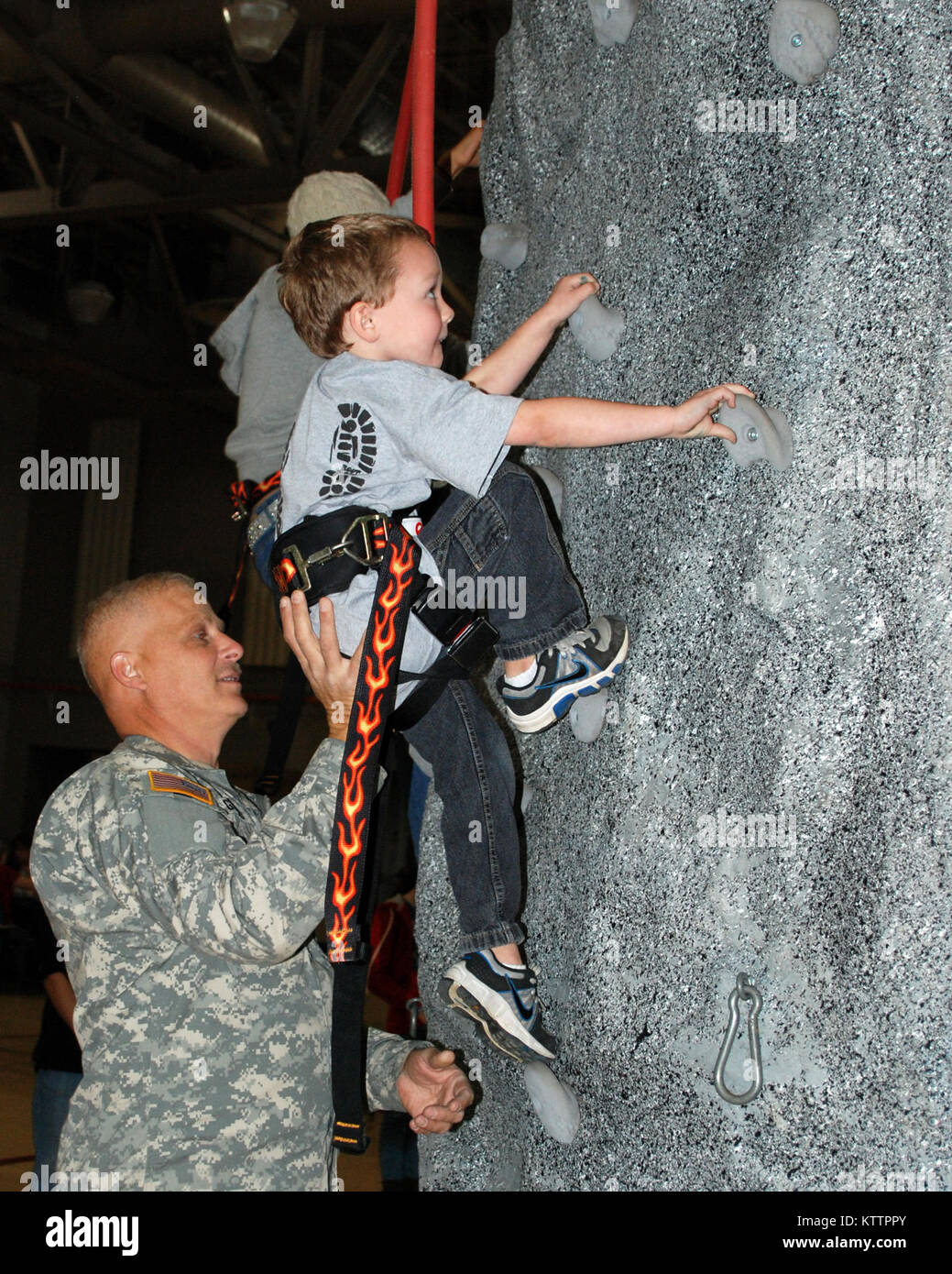 Latham -- New York Army National Guard Sgt. First Class David Girard gives Lucas Duff a boost onto a rock climbing wall at the National Guard headquarters on Nov. 11.     The Veterans Day event brought over 50 kids, from both military and non-military families from the Capital District area together to honor past and future hero's and support each other.  The youth assembled a quilt that will be sent to New York Army National Guard Soldiers serving overseas to remind them of their families back home.  Roughly 300 fabric quilt squares which include drawings and messages to Soldiers from childre Stock Photo