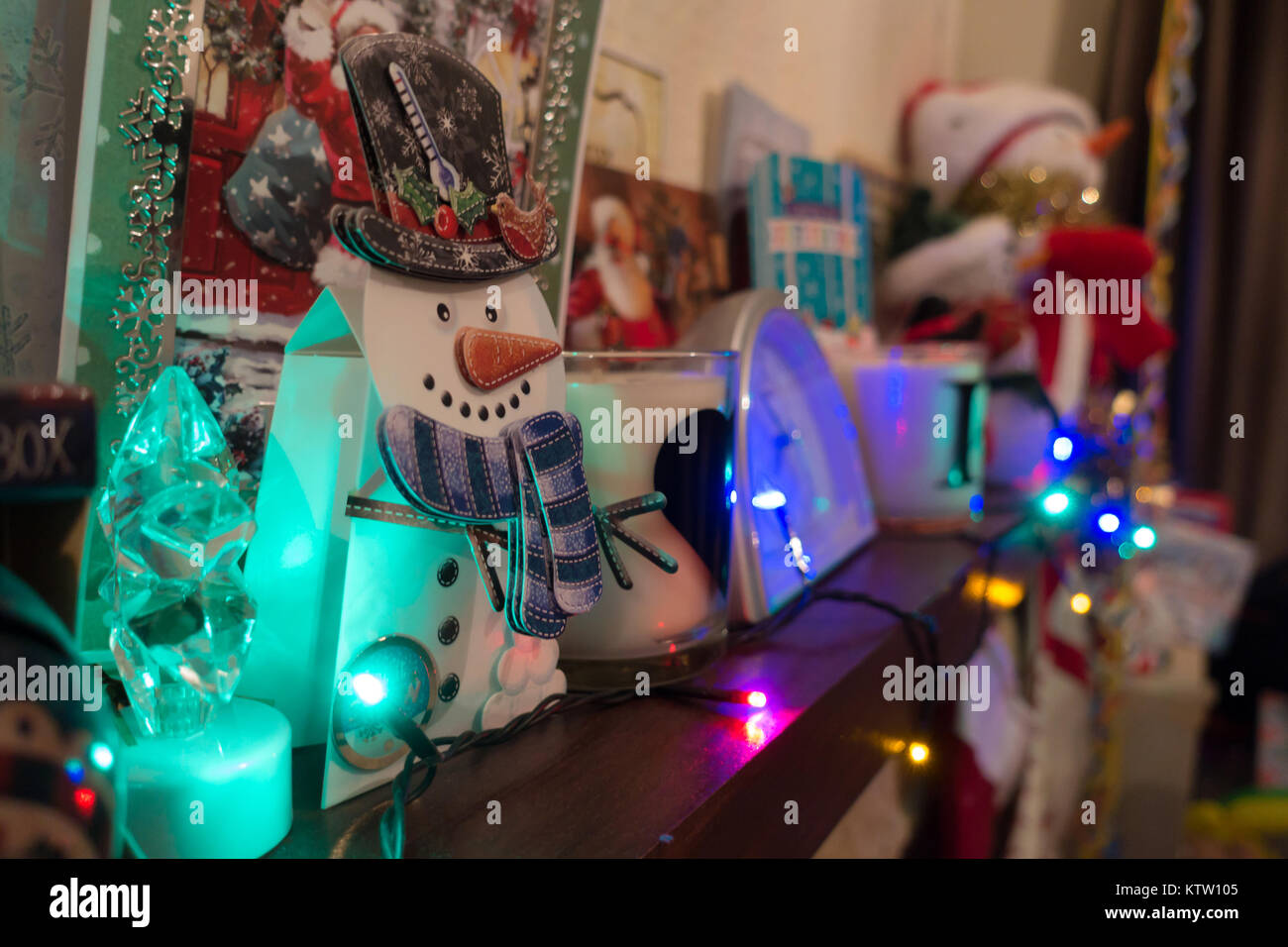 A mantelpiece decorated with Christmas decorations including Christmas tree lights cuddly toys and Christmas cards