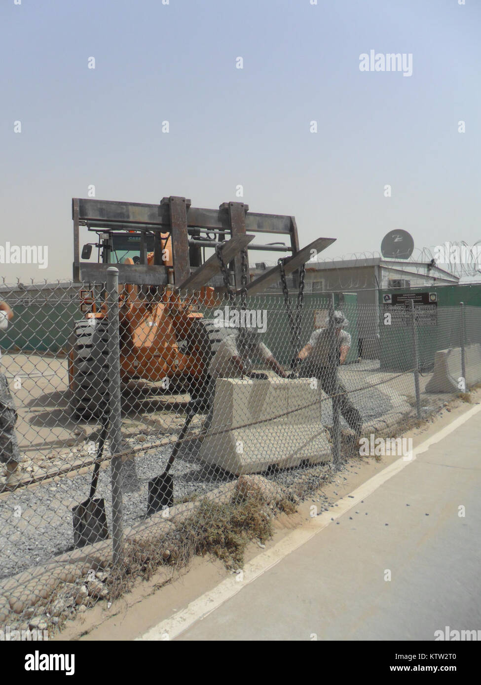 Staff Sgt. Miguel Santiago (left) and Sgt. Mike O’Rourke (right) direct and assist the movement of a concrete barrier at a base in Kuwait earlier this year. Santiago, of West Orange, N.J., and O’Rourke, of Camillus, N.Y. belong to the New York Army National Guard's 27th Infantry Brigade Combat Team (IBCT), and deployed here with 37 other brigade Soldiers in March to support ASG Kuwait. Santiago, O’Rourke and other Soldiers of the group formed the Base Defense Liaison Team (BDLT), which ranged all over Kuwait, evaluating defenses, training security personnel and arranging for the movement and i Stock Photo