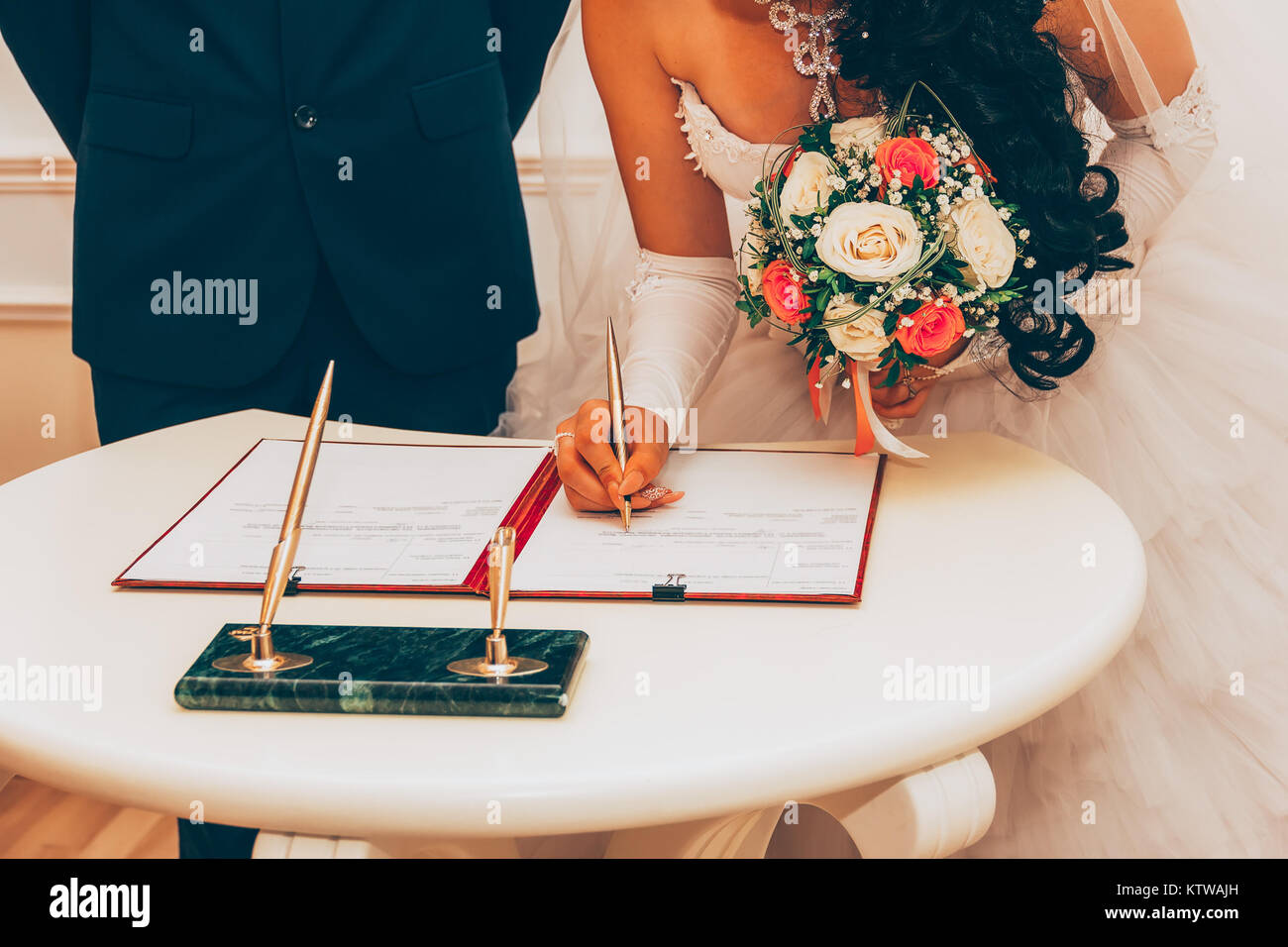 Wedding. Registration Of Marriage, The Bride With A Bouquet Of Flowers Signed A Marriage Contract A Golden Pen, Selective Focus. Tinted Image Stock Photo